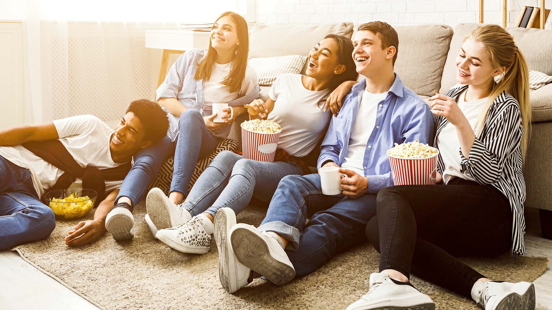 Jugendliche sitzen vorm Fernseher und essen Popcorn